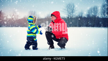 Vater mit Söhnen gehen bei Schneefall Stockfoto