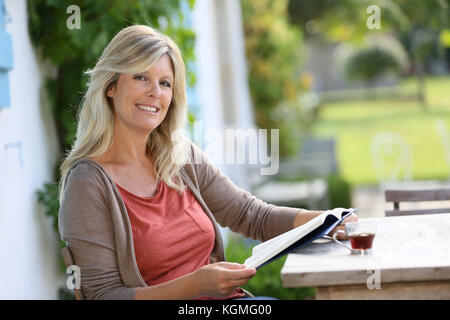 Reife Frau Lesung buchen Sie im Hinterhof Stockfoto