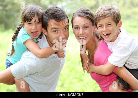 Portrait von glücklichen Eltern, die Kinder auf ihrem zurück Stockfoto