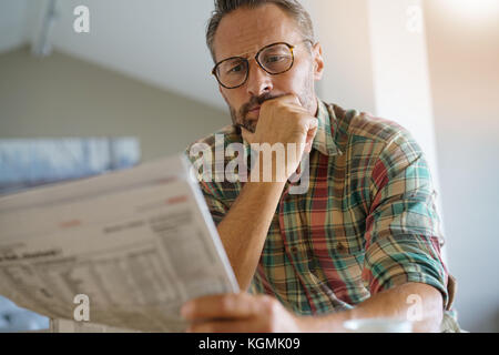 Stattliche reifer Mann zu Hause lesen Zeitung Stockfoto