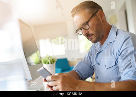 Home-office-Mitarbeiter mit Smartphone Stockfoto