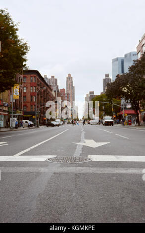 New York - Oktober 23, 2017: 9. Avenue crosswalk, Blick nach Norden Osten bis die Straße. selektive Fokus auf Kanaldeckel in Straße, mit Manhattan Gebäude Stockfoto