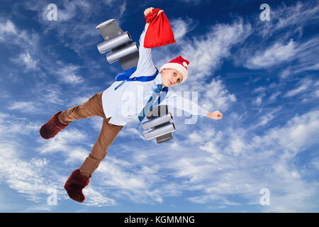 Junge santa claus Fliegen in den Himmel mit Geschenke für Weihnachten auf einem Jet Pack Stockfoto