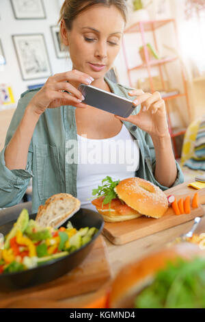 Trendige Mädchen im Restaurant die bunte Teller mit Smartphone Stockfoto