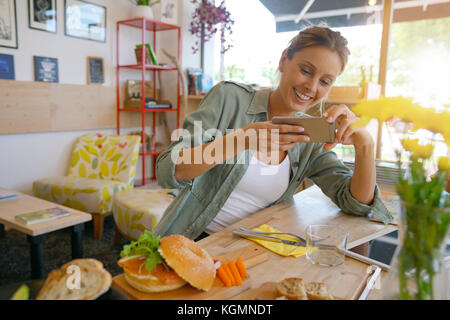 Trendige Mädchen im Restaurant die bunte Teller mit Smartphone Stockfoto