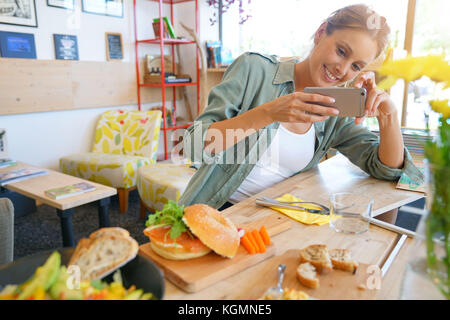 Trendige Mädchen im Restaurant die bunte Teller mit Smartphone Stockfoto