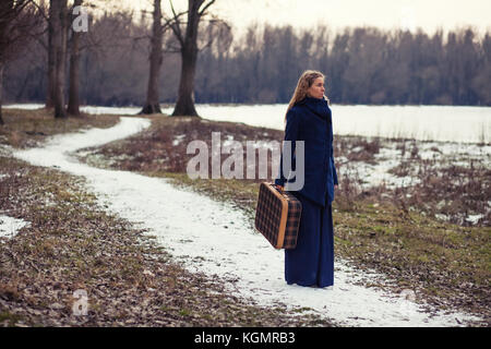 Frau Wandern in Wald mit alten Koffer Stockfoto