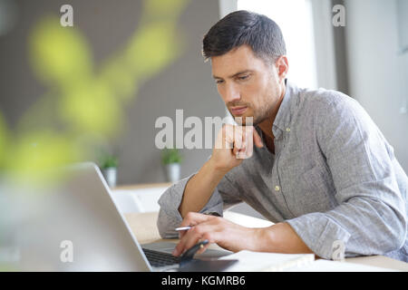 Mann im mittleren Alter, die von zu Hause aus arbeiten am Laptop. Stockfoto