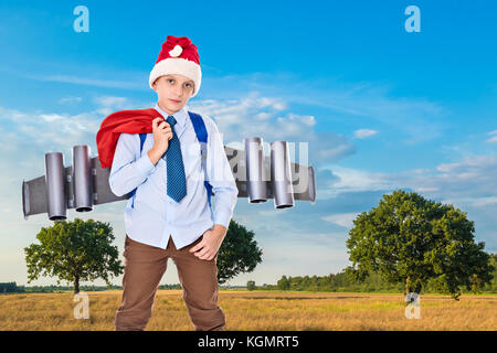 Junge Santa Claus mit einem Jetpack auf dem Rücken hält Geschenke für Weihnachten Stockfoto