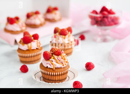 Leckere Himbeeren und Karamell Cupcakes auf weißem Hintergrund Stockfoto