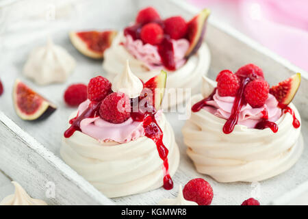 Leckere mini Pavlova baiser Kuchen mit frischen Himbeeren, Feigen und Berry Soße auf weißem Hintergrund Stockfoto