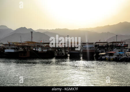 Blick auf die Boote am kleinen Hafen im Oman angedockt, wunderschönen Sonnenuntergang über al Hajar Berge Stockfoto