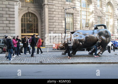 Leute, die Bilder mit dem berühmten Charging bull Statue in der Wall Street, New York. Stockfoto