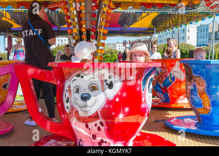 Kinder sitzen in Teetassen auf einer Fahrt auf einer Kirmes auf Margate Seafront, Kent. Stockfoto