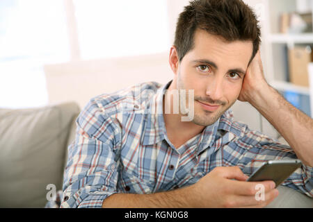 Schöner Mann zu Hause verwenden Smartphone Stockfoto