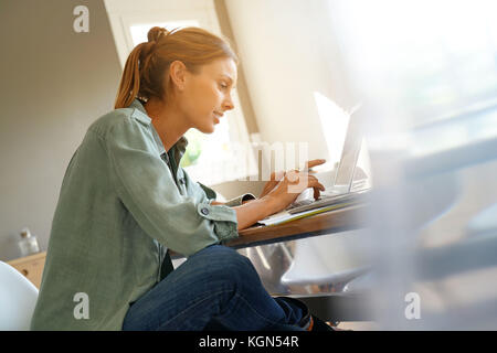 Trendige Mädchen von zu Hause aus arbeiten am Laptop Stockfoto