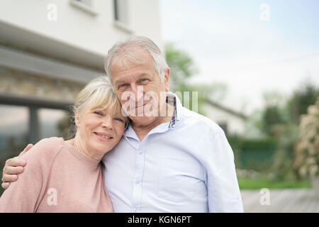 Senior Paar umarmen vor neuen modernen Haus Stockfoto