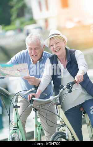 Senior paar Reiten Fahrräder und Lesen der Karte im touristischen Bereich Stockfoto