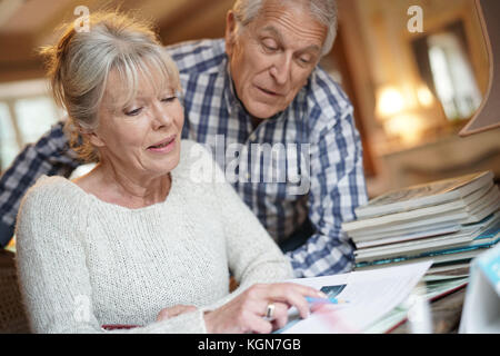 Senior paar Sitzen am Schreibtisch mit Blick auf Fotoalbum Stockfoto
