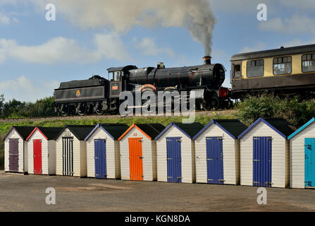 Dampfzug vorbei Holzhütten Am Goodrington Sands, geschleppt von GWR Lok Nr.7827 Lydham Manor. Stockfoto