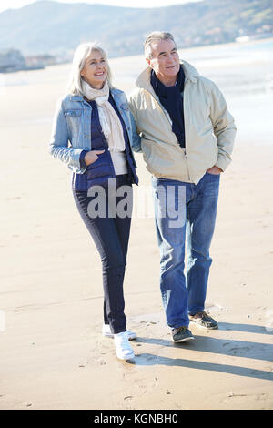 Senior Paar an einem Sandstrand im Winter Stockfoto