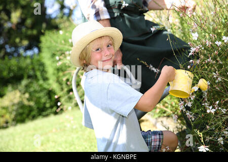 Nahaufnahme von niedlichen kleinen Jungen Blumen gießen im Garten Stockfoto