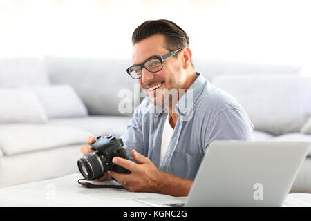 Mann an mit Spiegelreflexkamera home und Laptop Stockfoto
