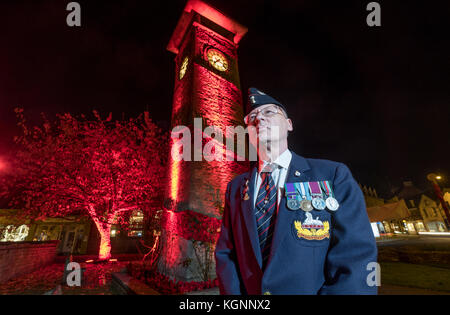 Nailsworth, Gloucestershire, Großbritannien, 10. November 2017. Der ehemalige Soldat Desmond Cox, der in der Grafschaft Gloucestershire Regiment gedient, dargestellt durch die Clock Tower im Zentrum von Nailsworth, die mit Mohn eingerichtet wurde und in rot beleuchtet, vor Der Armistice Day und Erinnerung Sonntag. Credit: Gavin Crilly/Alamy leben Nachrichten Stockfoto