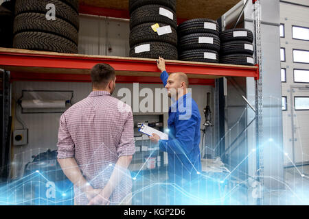 Kfz-Mechaniker und Mann mit Reifen bei Car shop Stockfoto