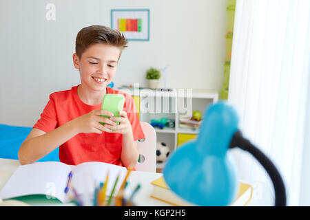 Schüler Junge mit Smartphone störende aus der Studie Stockfoto