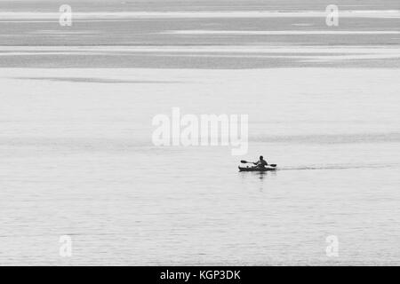 Schwarz/Weiß-Bild des Meeres Angler im Kajak gegen Wasser. Die Fischerei auf Makrele in flachen Gewässern in der Nähe von Par, Cornwall. Die Isolation. Stockfoto