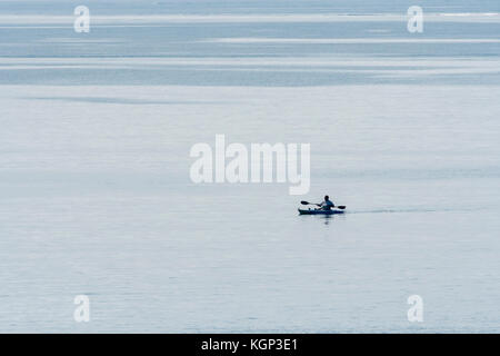 Einsame Meer angler paddeln Kajak gegen Wasser. Die Fischerei auf Makrele in flachen Gewässern in der Nähe von Par, Cornwall. Isolation Konzept. Stockfoto