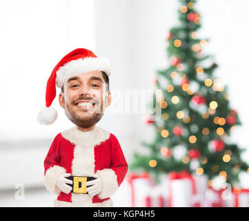 Urlaub und Personen Konzept - Glücklich lächelnde junge Mann in santa claus Kostüm über Weihnachtsbaum und Geschenke Hintergrund (lustig Cartoon Stil characte Stockfoto