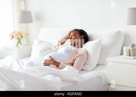 Schwangerschaft, Rest, Menschen und Erwartung Konzept - schwangere afrikanische amerikanische Frau schlafen im Bett zu Hause Stockfoto