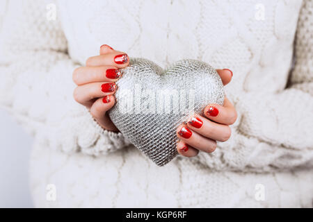 Die frau Hände mit schönen genaue Maniküre sorgfältig aufbewahren Silber Herz Stockfoto