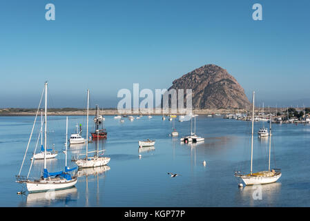 Anzeigen von Morro Rock über Morro Bay mit Segelbooten in Stille Wasser verankert wie ein Vogel durch die an einem sonnigen Morgen fliegt. Stockfoto