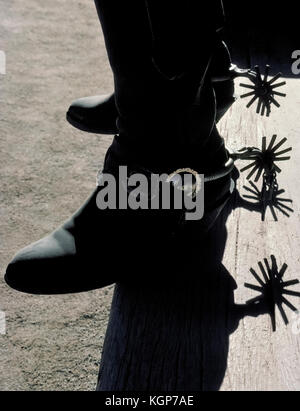 Die spurs aus Metall und Leder Stiefel eines amerikanischen Cowboy sind silhouetted, als er Schritte, eine hölzerne Veranda Schritt bei einer Western Guest Ranch in Arizona, USA. Stockfoto