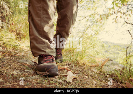 Wanderschuhe mit Red Laces und Beine tragen lange braune Hose von einem Wanderer zu Fuß auf den Weg in den Wald. Vintage Effekt Stockfoto