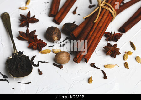 Mischung aus getrockneten Spione für indische Masala Chai oder würzigen Tee: Anis, Kardamom, Zimt, Muskatnuss, Nelke und schwarzer Tee auf weißem Hintergrund Stockfoto