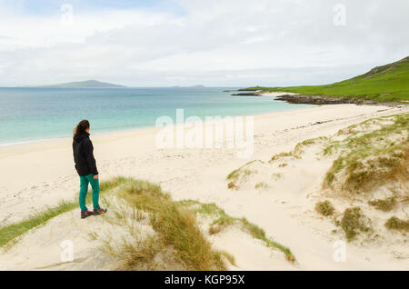 Junge Frau von hinten bewundern Sie einen leeren weißen Sandstrand auf den Äußeren Hebriden, Schottland, Großbritannien. Stockfoto