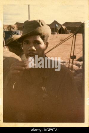 Offenes Porträt eines afroamerikanischen Soldaten, der während des Vietnamkriegs 1968 ein Sandwich zwischen Zelten auf einer amerikanischen Militärbasis in Vietnam isst. Stockfoto