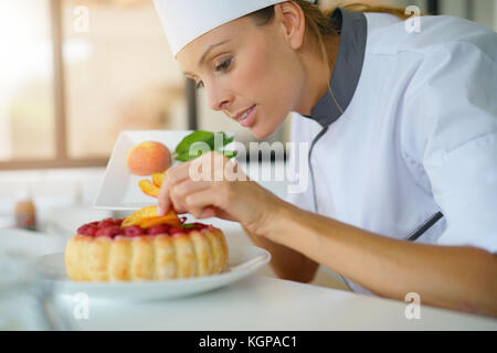 Konditor in der professionellen Küche Dekoration himbeere Kuchen mit Früchten Stockfoto