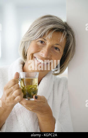 Ältere Frau im Bademantel trinken heißen Grüner Tee Stockfoto