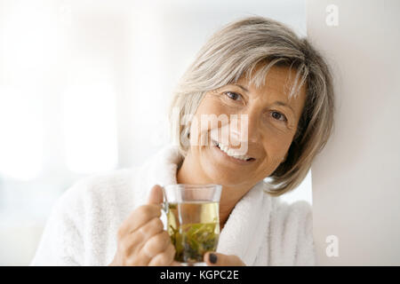 Ältere Frau im Bademantel trinken heißen Grüner Tee Stockfoto