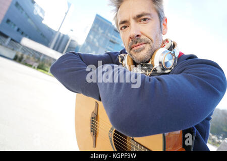 Musiker sitzt auf der Bank mit Gitarre genießt sonnigen Tag Stockfoto