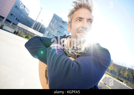 Musiker sitzt auf der Bank mit Gitarre genießt sonnigen Tag Stockfoto