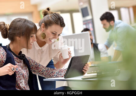 Junge Frauen im Amt arbeiten an digitalen Tablet