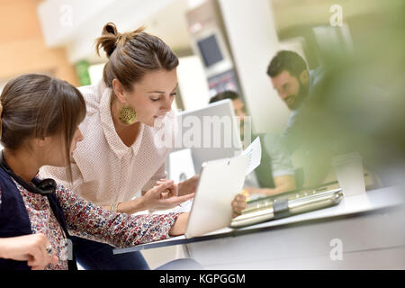 Junge Frauen im Amt arbeiten an digitalen Tablet