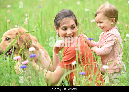 Frau und Baby Mädchen spielen mit Golden Retriever Hund Stockfoto