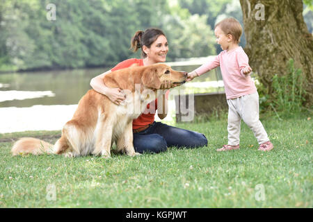 Frau und Baby Mädchen spielen mit Golden Retriever Hund Stockfoto